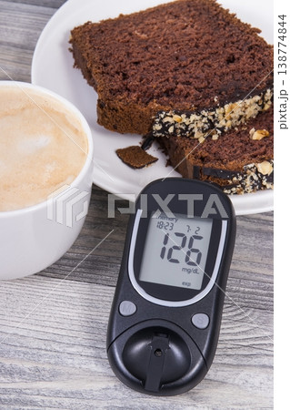 Glucose meter with result sugar level, sweet chocolate cake and cup of coffee with milk Glucose meter with result sugar level, sweet chocolate cake and cup of coffee with milk 138774844