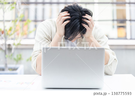 パソコンの前で頭を抱える若い男性 138775593