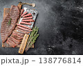 Juicy sliced outside skirt beef steak with herbs and knife on wooden board, grilled meat with visible fibers and medium rare doneness 138776814
