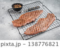 Grilled beef steaks on cooling rack with seasoning and pepper, juicy cooked meat ready to serve, homemade dinner or barbecue food concept 138776821