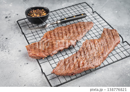 Grilled beef steaks on cooling rack with seasoning and pepper, juicy cooked meat ready to serve, homemade dinner or barbecue food concept 138776821