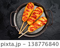 Golden corn dogs with ketchup topping served on plate with sauce, crunchy fast food snack on dark background 138776840