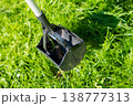 Pooper scooper on green grass in sunlight for pet waste cleanup 138777313