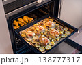 A baking tray with French-style pork, potatoes, mushrooms, and cheese, alongside baked chicken  138777317