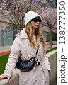 Stylish woman in spring outfit wearing sunglasses and a bucket hat in the city. 138777350
