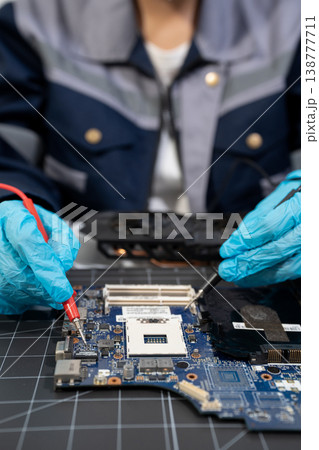 Computer Hardware Technician Repairing Motherboard with Soldering Iron in Electronics Lab. 138777711