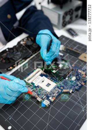 Computer Hardware Technician Repairing Motherboard with Soldering Iron in Electronics Lab. Computer Hardware Technician Repairing Motherboard with Soldering Iron in Electronics Lab. 138777712