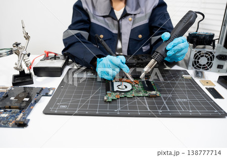 Computer Hardware Technician Repairing Motherboard with Soldering Iron in Electronics Lab. 138777714