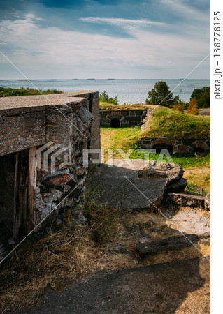 view of historic concrete bunkers and defensive structures built into the grassy landscape overlooking the Baltic Sea at the Suomenlinna fortress near Helsinki, Finland. 138778125