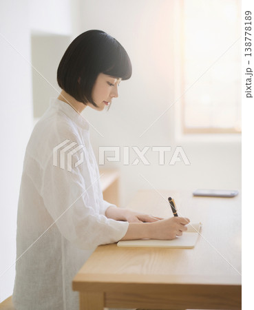 机でノートに書き込む女性の横顔と集中する姿 138778189