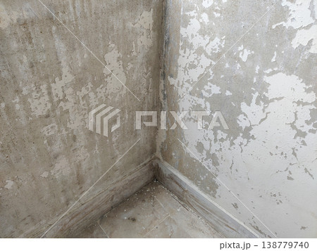 Wall corner and floor area with peeling paint exposing plaster due to water seepage damage 138779740