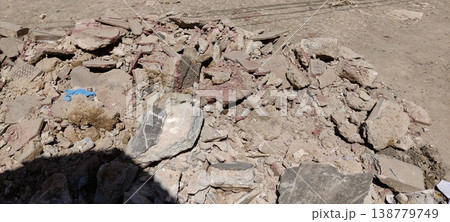 Demolition waste with cracked concrete chunks and dusty brown rubble in outdoor construction site 138779749