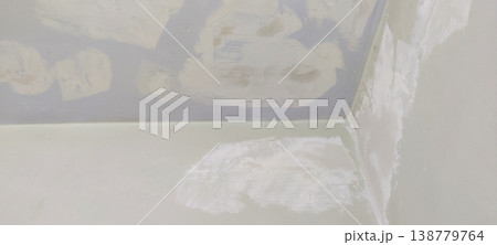 Wall and ceiling corner with putty patches and off white base color showing repair stage 138779764