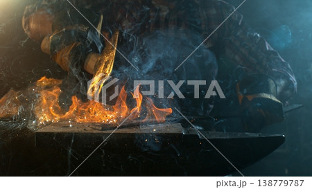 Close-up of blacksmith forging glowing hot iron on anvil with flying sparks 138779787