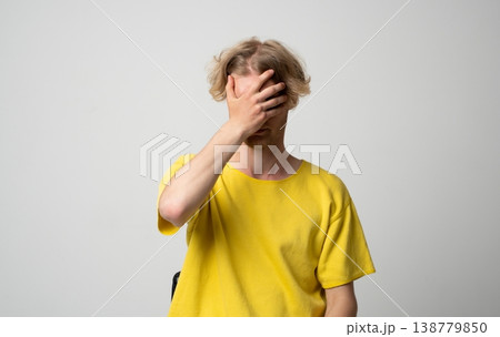Frustrated young man covering his face with his hand, showing shame, stress, and disappointment, making a mistake or facing failure and embarrassment Frustrated young man covering his face with his hand, showing shame, stress, and disappointment, making a mistake or facing failure and embarrassment 138779850