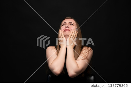 Young woman covering her face while crying, experiencing sadness, grief, and emotional pain against a dark background Young woman covering her face while crying, experiencing sadness, grief, and emotional pain against a dark background 138779866