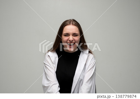 Young woman bursting with laughter, expressing joy and genuine happiness in a studio portrait Young woman bursting with laughter, expressing joy and genuine happiness in a studio portrait 138779874