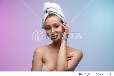 Woman applying under eye patches for skin care routine, wearing a towel wrap, enjoying beauty treatment and self-care moment at home with glowing skin Woman applying under eye patches for skin care routine, wearing a towel wrap, enjoying beauty treatment and self-care moment at home with glowing skin 138779883