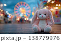 Cute plush bunny toy at amusement park with ferris wheel lights at night 138779976