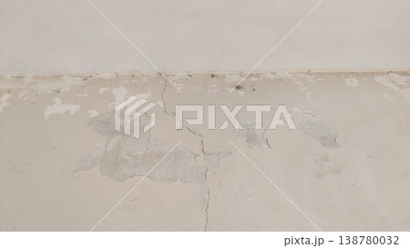 Peeling paint along cracked wall base showing signs of moisture decay 138780032