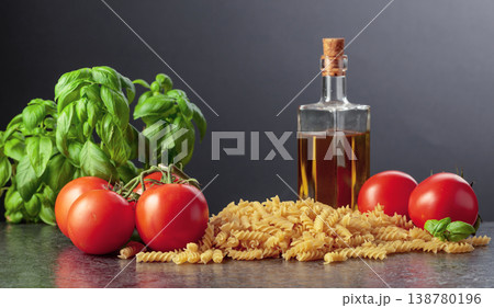 Fusilli pasta with olive oil, tomatoes and basil on a black background. Fusilli pasta with olive oil, tomatoes and basil on a black background. 138780196