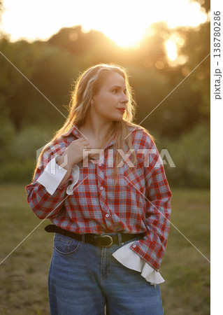 Contemplative Young Woman Standing Outdoors During Sunset With Warm Rim Light And Relaxed Pose Contemplative Young Woman Standing Outdoors During Sunset With Warm Rim Light And Relaxed Pose 138780286