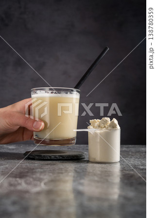 Protein vanilla shake and scoop with whey protein powder on dark background, female hand 138780359