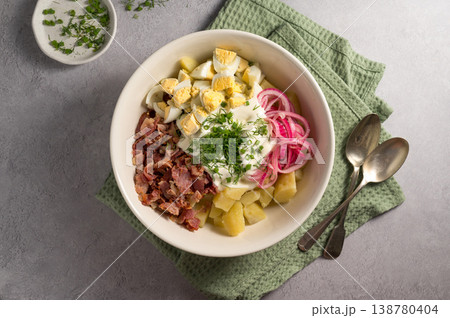 Egg potato salad with bacon and fresh herbs in a plate 138780404