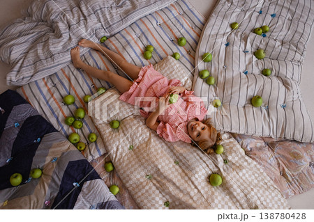Little girl lying on mattresses with green apples, top view, princess and the pea concept Little girl lying on mattresses with green apples, top view, princess and the pea concept 138780428