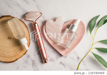 Rose quartz gua sha tool and face massage roller on wooden tray, beauty abstract photo. Top view 138780469