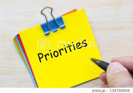 Priorities written on yellow sticky note representing focus and decision making at work. 138780608