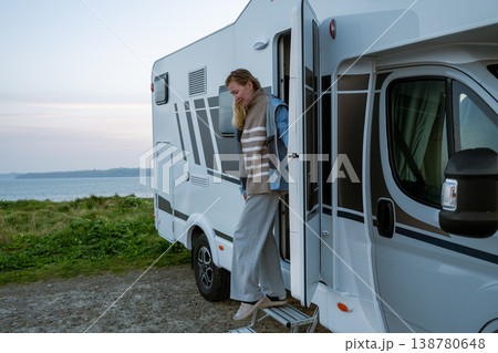 Woman standing in campervan doorway enjoying Atlantic ocean view Woman standing in campervan doorway enjoying Atlantic ocean view 138780648