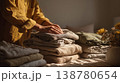 Woman folding clean clothes in warm sunlight cozy home interior 138780654