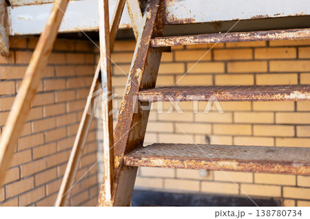 Corroded urban fire escape. Textured exterior staircase with flaking rust and gritty details 138780734