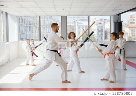 Children practicing karate with bokken under instructor guidance Children practicing karate with bokken under instructor guidance 138780803