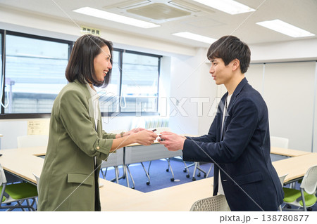 会議室で笑顔で名刺交換をする男女のビジネスパーソン 会議室で笑顔で名刺交換をする男女のビジネスパーソン 138780877