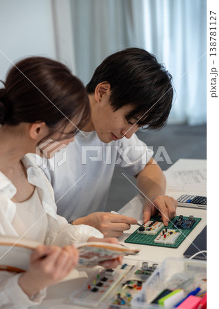 テキストを見ながら電子回路を勉強している若い男女 テキストを見ながら電子回路を勉強している若い男女 138781127