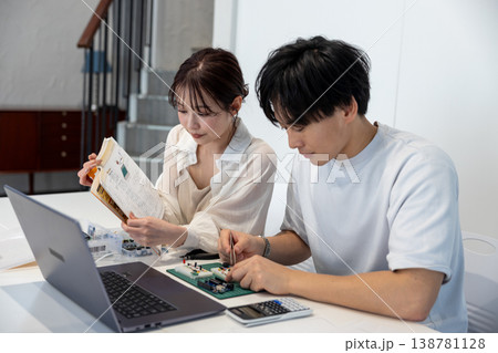 テキストを見ながら電子回路を勉強している若い男女 テキストを見ながら電子回路を勉強している若い男女 138781128