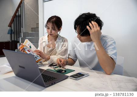 テキストを見ながら電子回路を勉強している若い男女 テキストを見ながら電子回路を勉強している若い男女 138781130