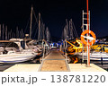 Night marina pier between moored yachts under dark starry sky navigation lights reflecting calm water. Harbor dock perspective boats masts ropes walkway travel luxury sailing lifestyle atmosphere 138781220