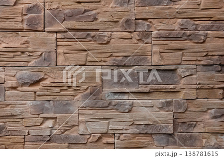 Textured stone wall featuring a natural, rustic design with warm tones and intricate patterns in a contemporary setting 138781615