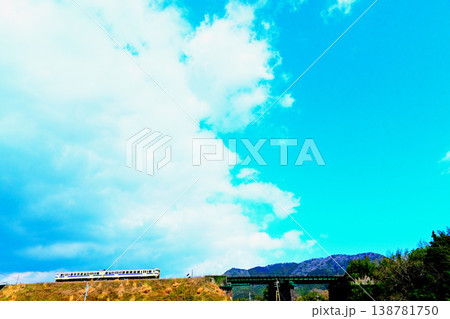 青空と雲の下を走る電車 138781750