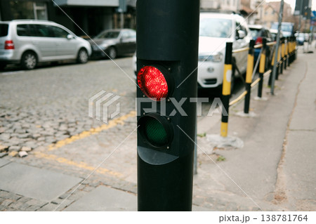 Red traffic light on a city street near parked cars and roadside barriers. Everyday urban scene about parking regulation, traffic control and city infrastructure Red traffic light on a city street near parked cars and roadside barriers. Everyday urban scene about parking regulation, traffic control and city infrastructure 138781764