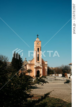 Minimalist view of church tower with cross against clear blue sky in Sombor, Serbia, calm architecture and religious landmark. Minimalist view of church tower with cross against clear blue sky in Sombor, Serbia, calm architecture and religious landmark. 138781997
