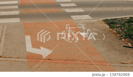 Bicycle lane marking with white bike symbol and directional arrow on urban road surface near pedestrian crossing. Concept of sustainable transport, cycling infrastructure and safe city mobility Bicycle lane marking with white bike symbol and directional arrow on urban road surface near pedestrian crossing. Concept of sustainable transport, cycling infrastructure and safe city mobility 138782008