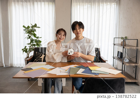 大小の家のクラフトを持ってこっちを向いている若いカップル 大小の家のクラフトを持ってこっちを向いている若いカップル 138782522