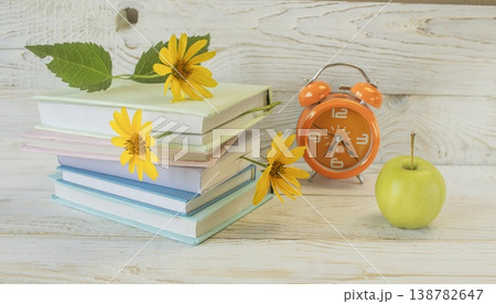 Back to school still life with books, flowers, alarm clock and apple on wooden background. Colorful school still life. 138782647