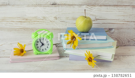 Back to school still life with books, flowers, alarm clock and apple on wooden background. Colorful school still life. Back to school still life with books, flowers, alarm clock and apple on wooden background. Colorful school still life. 138782651