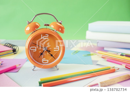 Study table with alarm clock, colorful pencils, colored paper and books. Learning concept, back to school Study table with alarm clock, colorful pencils, colored paper and books. Learning concept, back to school 138782734