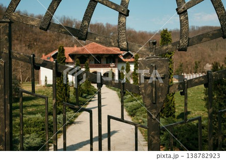 Iron gate with Christian cross leading to Ribnica Monastery courtyard near Mionica Serbia. Religious architecture representing faith spirituality pilgrimage tradition sacred heritage tourism Iron gate with Christian cross leading to Ribnica Monastery courtyard near Mionica Serbia. Religious architecture representing faith spirituality pilgrimage tradition sacred heritage tourism 138782923